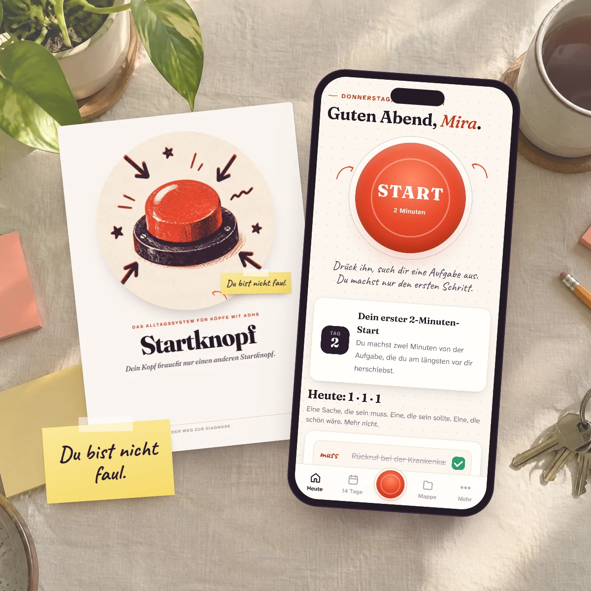 Das Startknopf-Buch, die App auf dem Handy und ein Zettel: Du bist nicht faul.